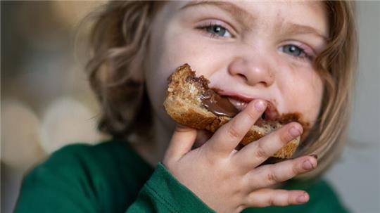 Ein Junge isst ein Brot mit Nutella.